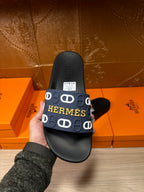 Hermes black slide sandal held in hand, navy strap with white H logo
