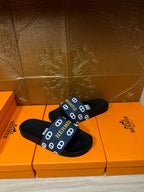 Hermes black slide sandals with navy strap and repeating white H emblems