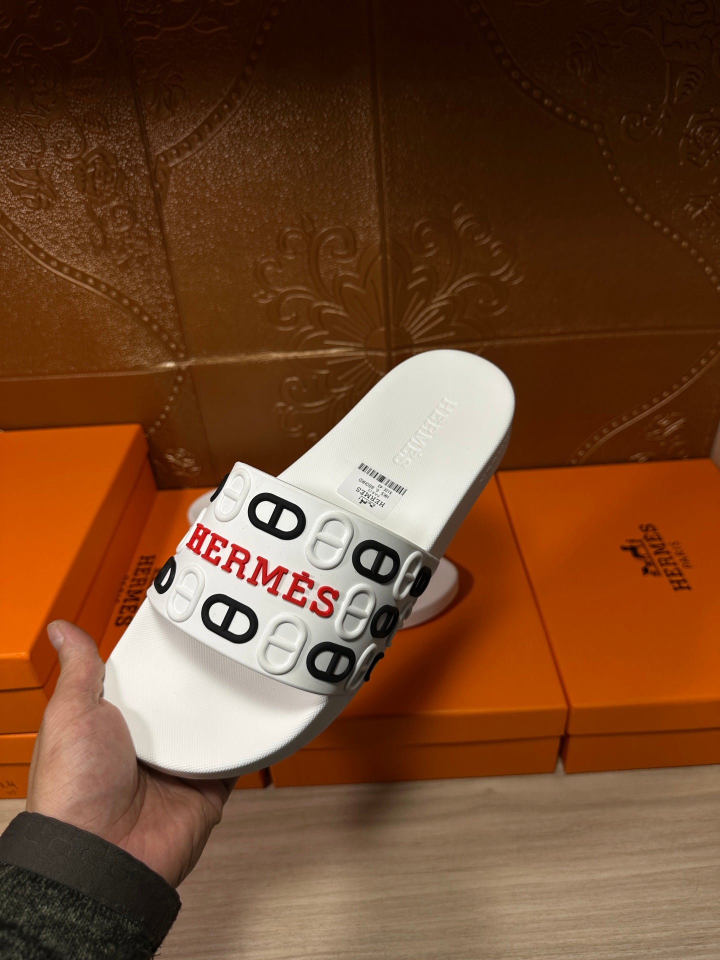 Hermes white slide sandals held up, showing the footbed and logo strap