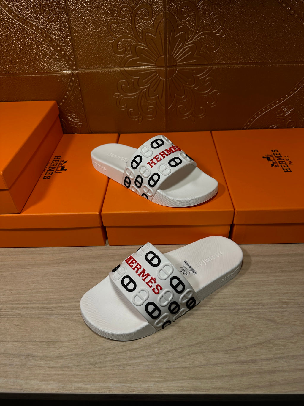 Hermes logo slide sandals in white, angled view of the wide strap
