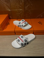 Hermes logo slide sandals in white, angled view of the wide strap