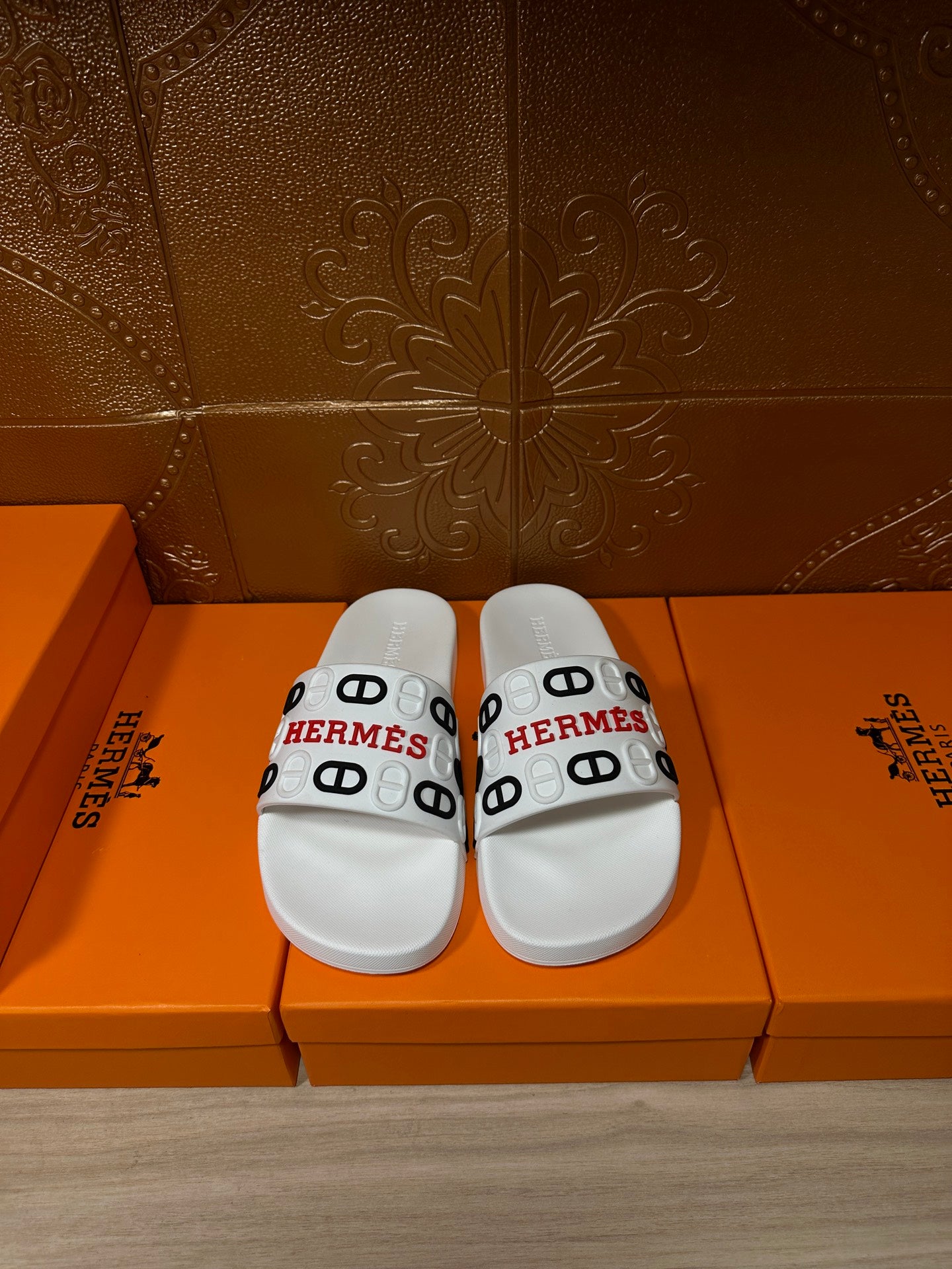 Hermes slide sandals in white with black and red logo band across the straps