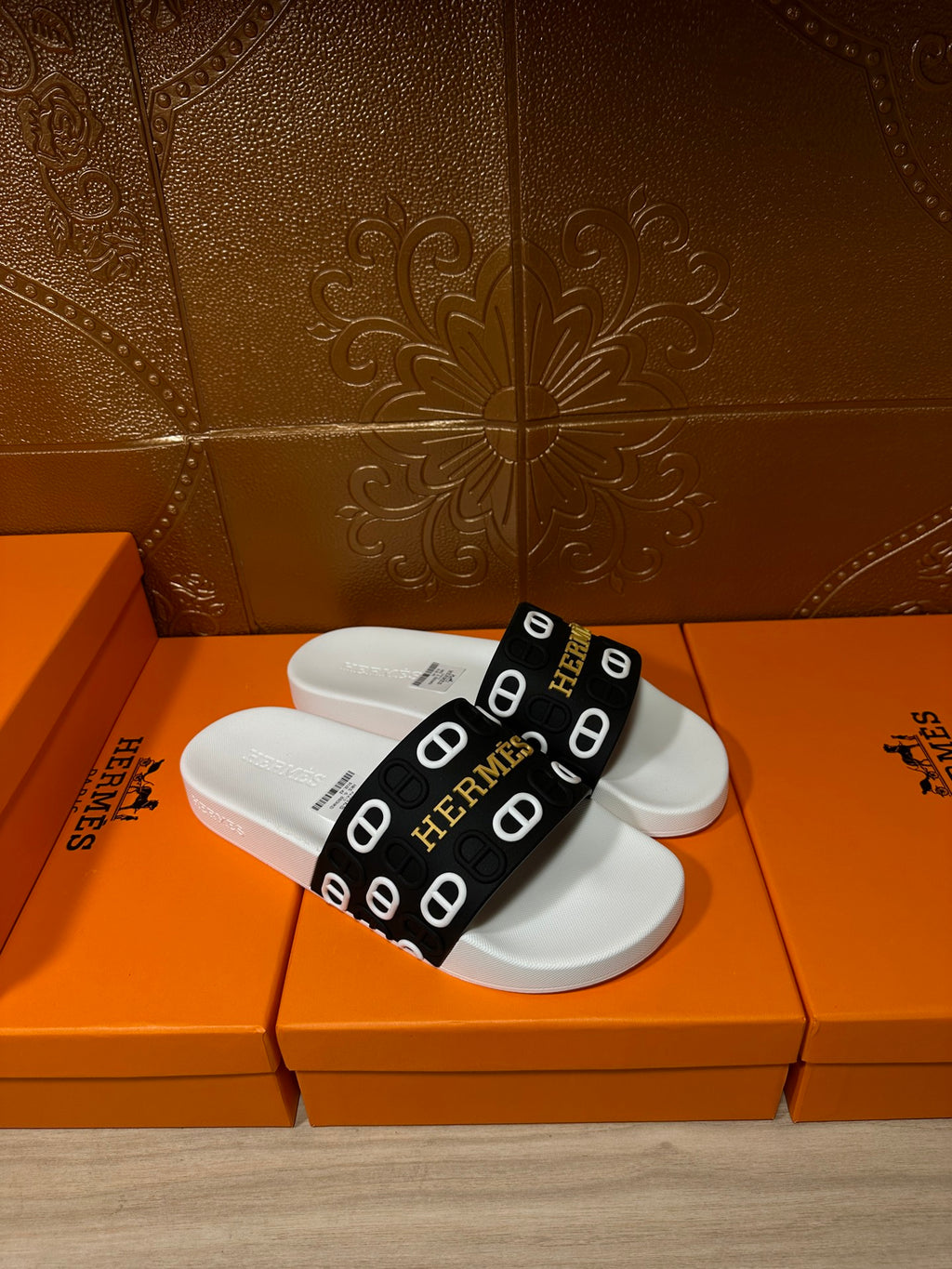Hermès sandals with black-and-white logo strap and white cushioned footbeds.