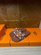Hermes slide sandals with dark brown slide strap and logo detail, flat sole
