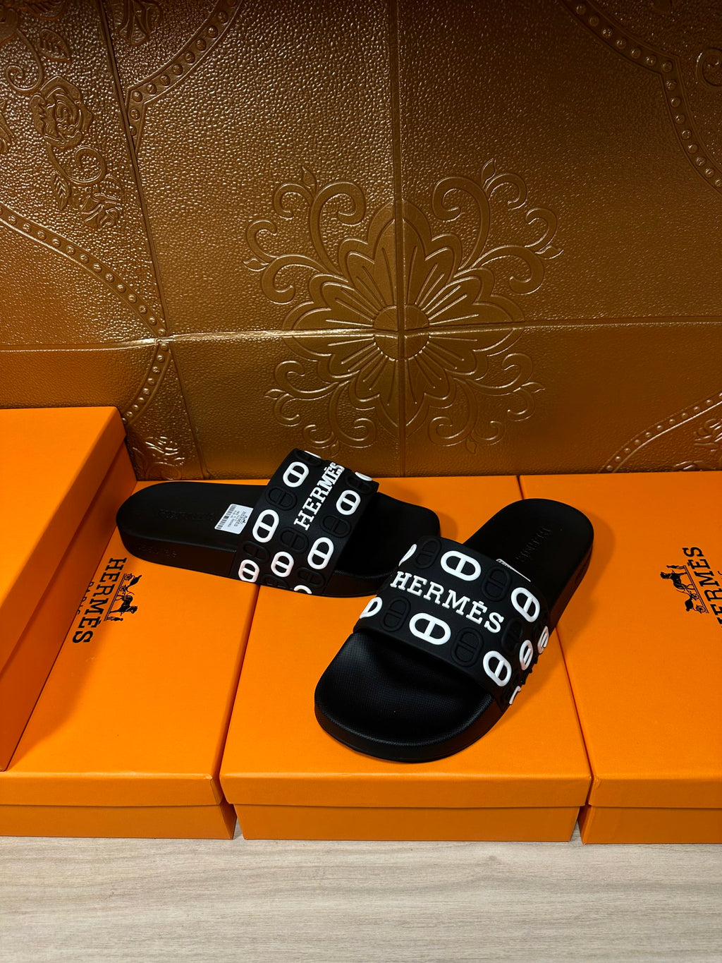 Black slide sandals with wide HERMES logo strap and flat rubber footbed