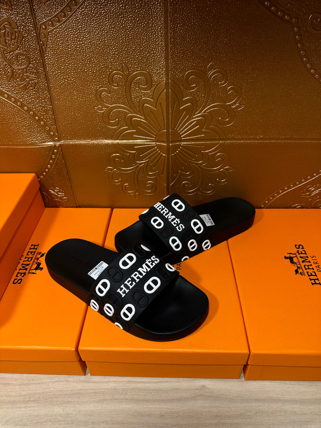 Black slide sandals with HERMES logo strap across the foot, open-toe design