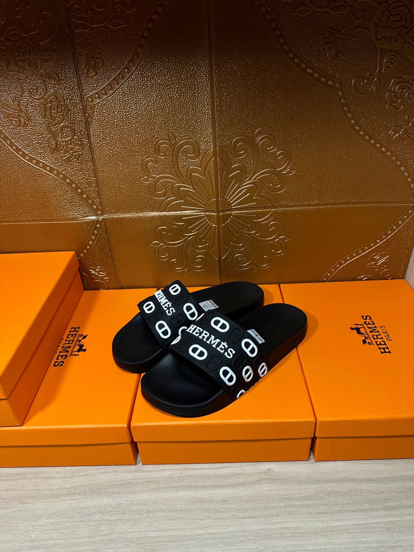 Black slide sandals with wide HERMES logo strap, open toe and textured footbed