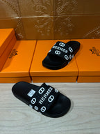 Black slide sandals, pair shown with HERMES logo strap and textured black sole