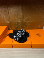 Black slide sandals with HERMES logo strap, angled top view