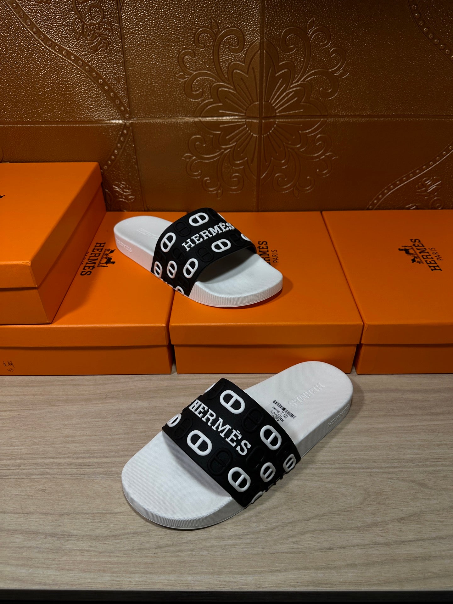 White slide sandal with black strap showing Hermes logos, side view