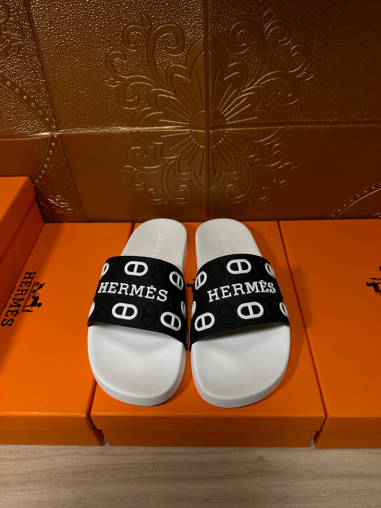 White slide sandal with black Hermes logo strap and repeated monogram pattern