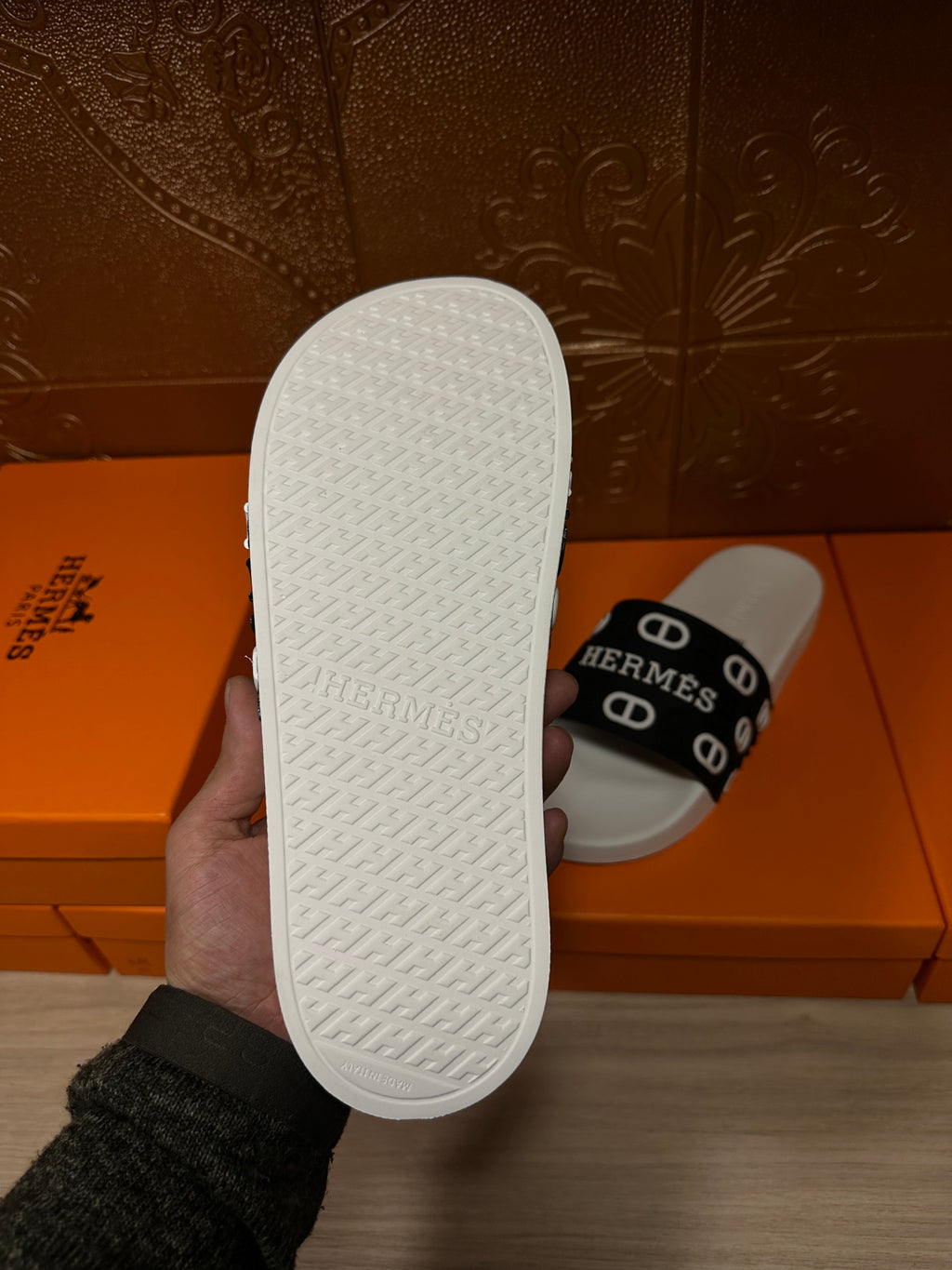 White textured rubber outsole of a slide sandal with black Hermes logo strap
