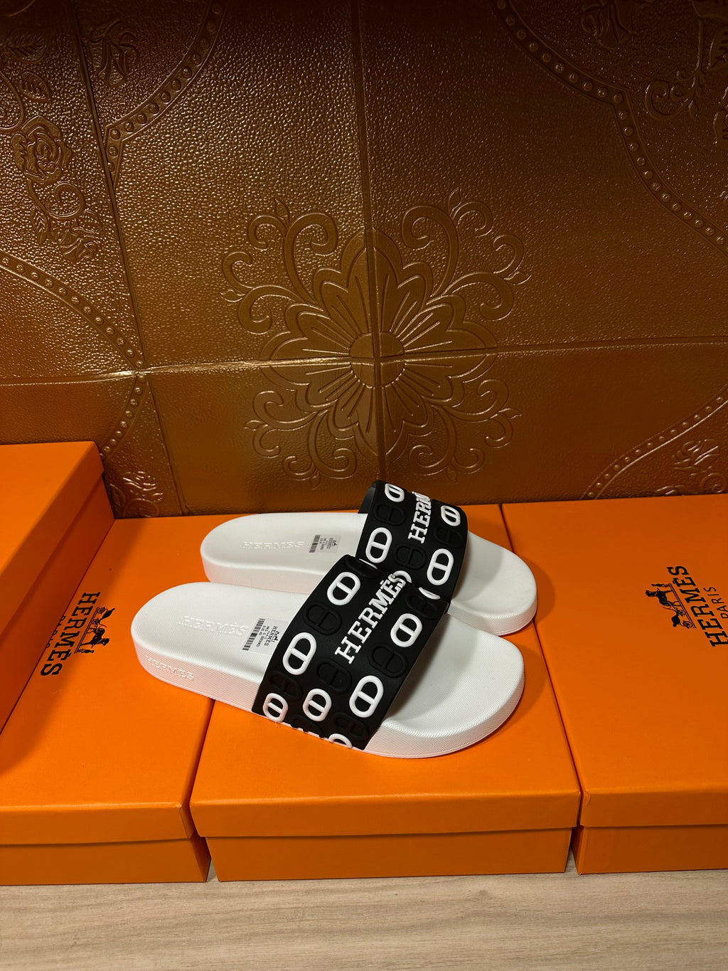 White slide sandal with black band strap printed with Hermes letters and icons