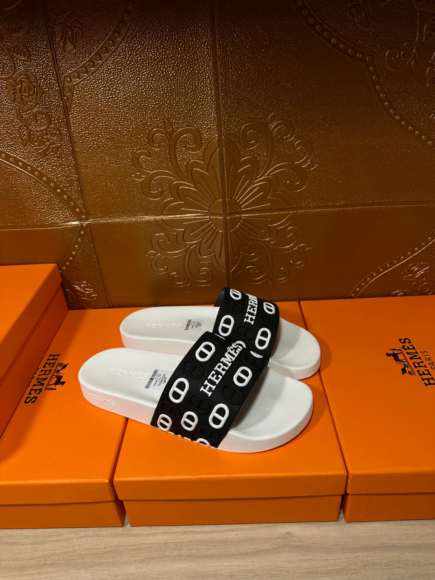 White slide sandal with black band strap printed with Hermes letters and icons