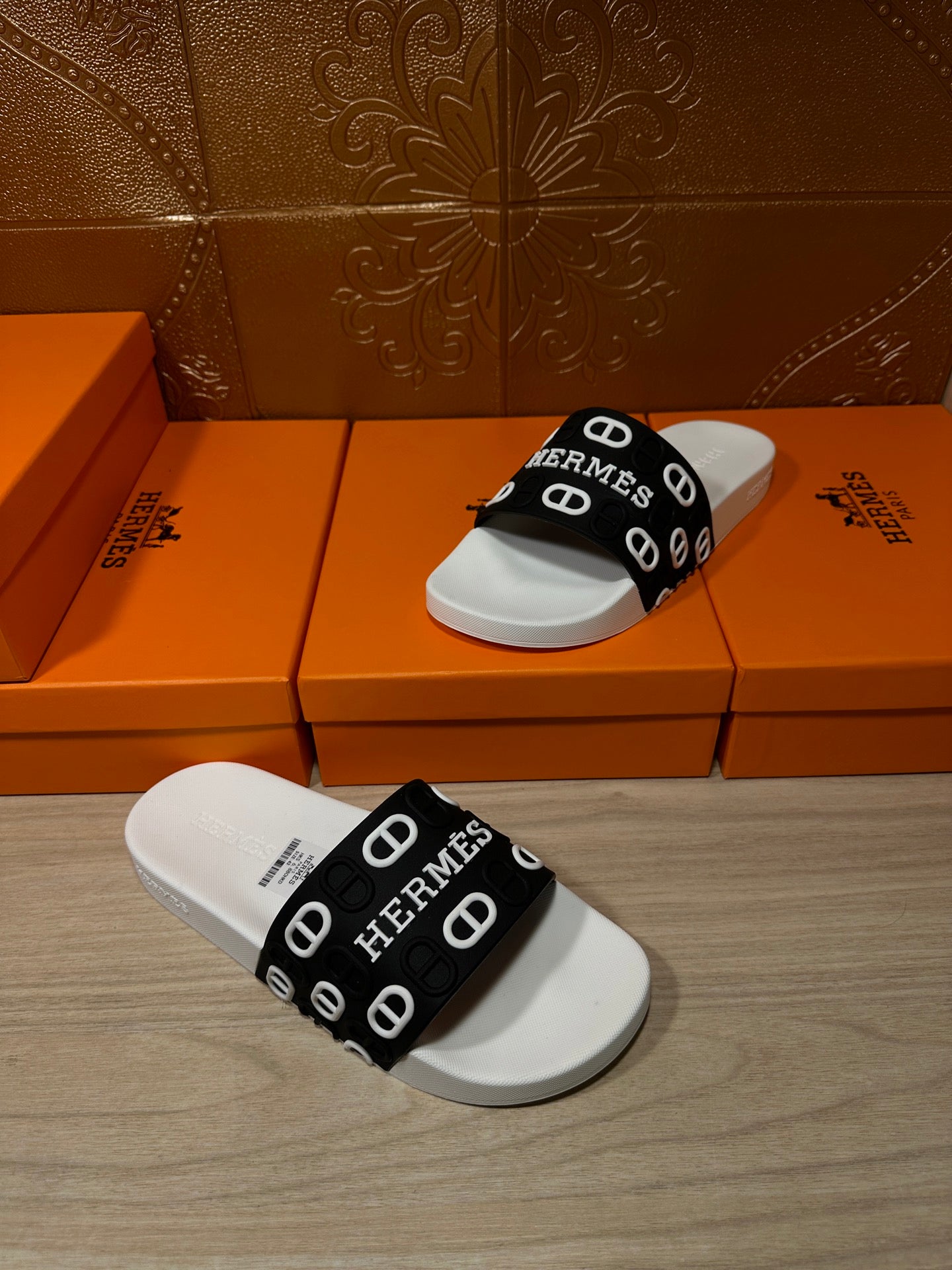 White slide sandal with black Hermes logo strap, angled view with curved footbed