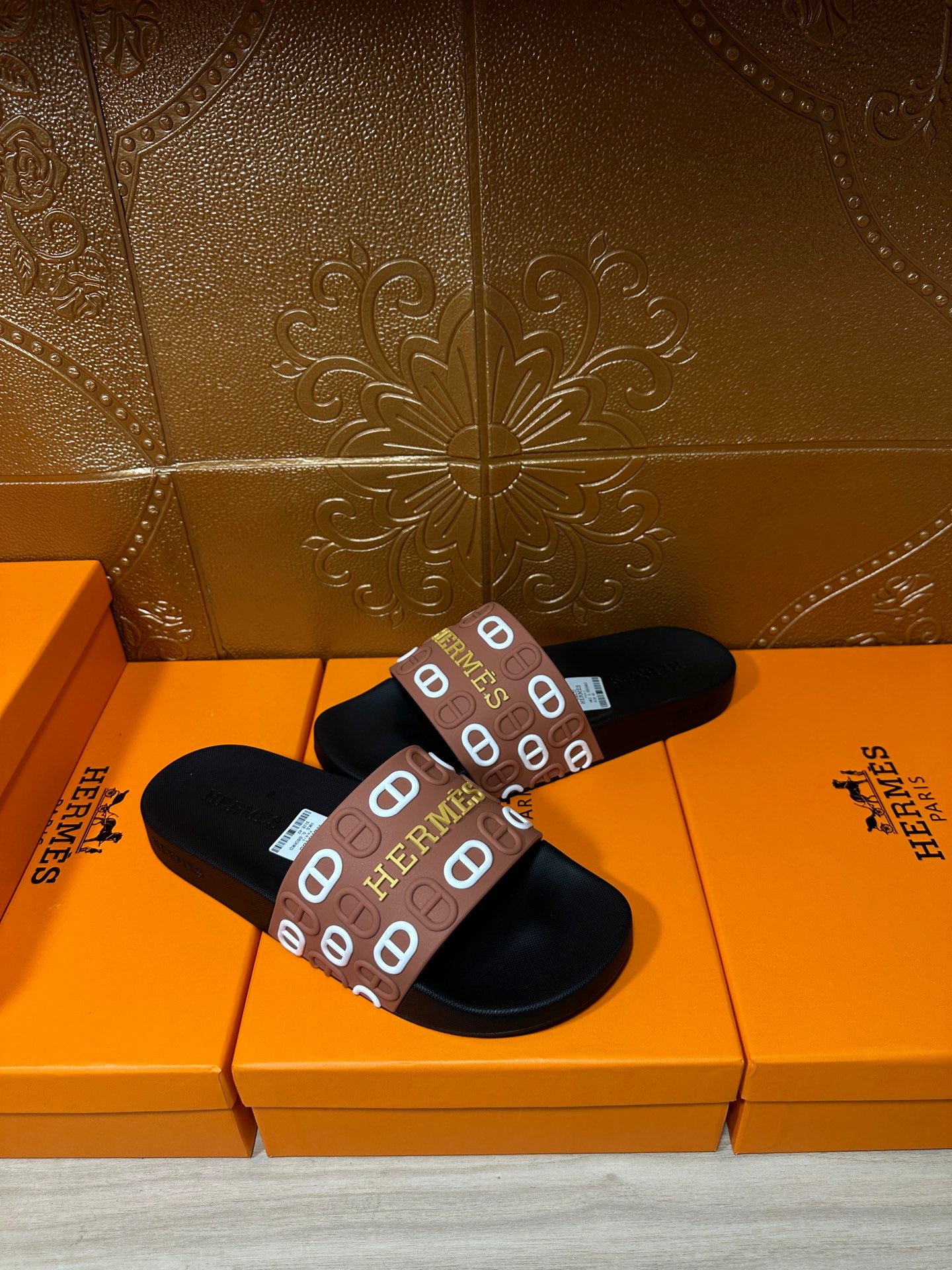 Black slide sandals with brown Hermes logo band, angled view