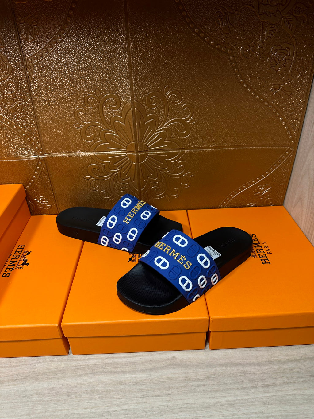 Black slide sandals with blue Hermes-logo strap, worn look from side/front.