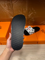 Black slide sandal outsole with textured tread; Hermes logo strap shown.