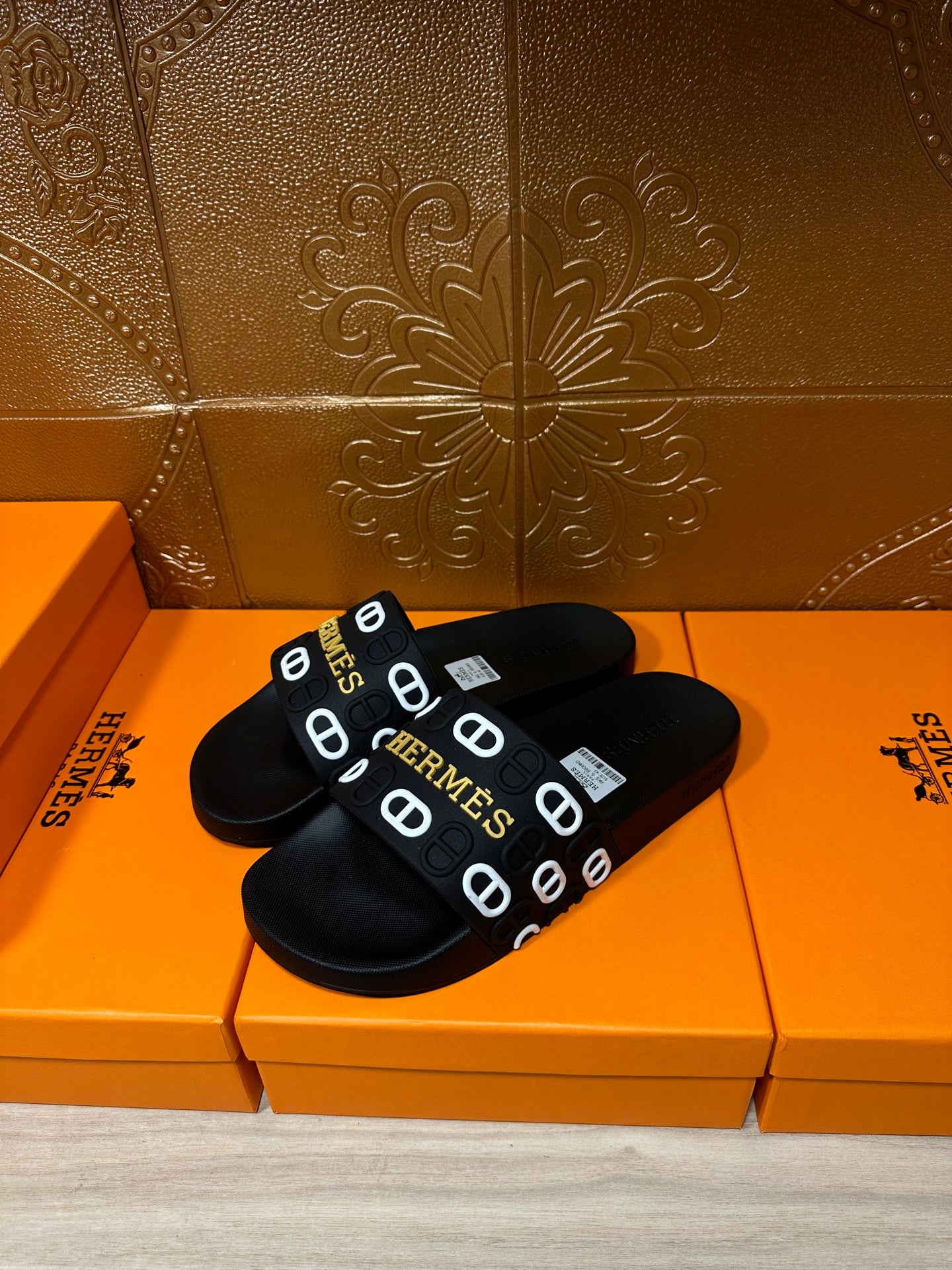 Black slide sandals with repeating Hermes logo strap, pair