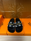 Black slide sandals with Hermes logo strap and round open toe, pair