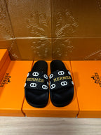 Black slide sandals with Hermes logo strap and round open toe, pair