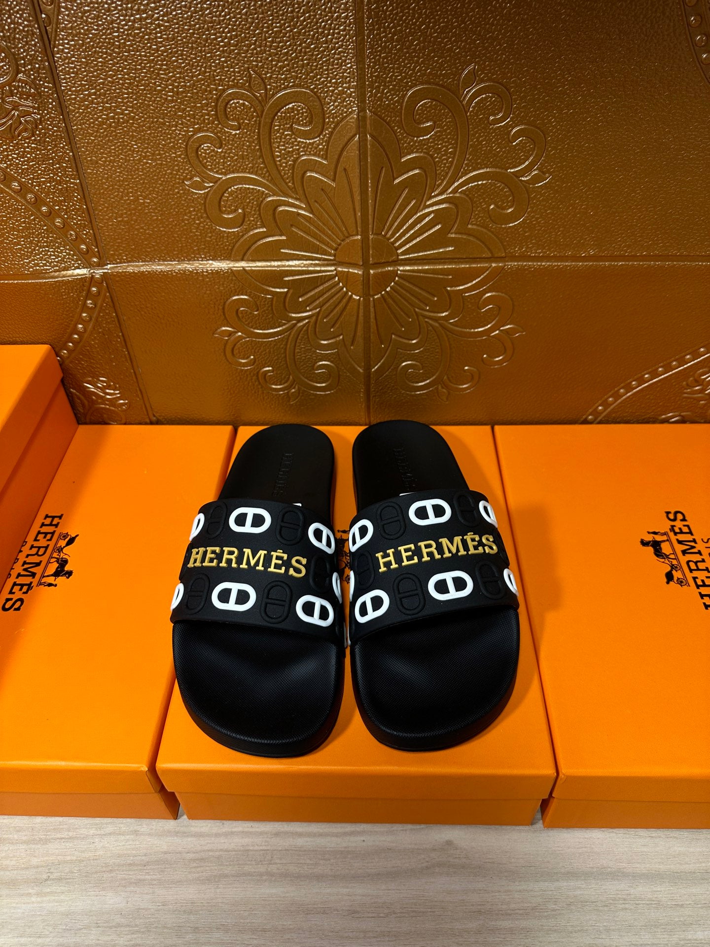Black slide sandals with Hermes logo strap and round open toe, pair