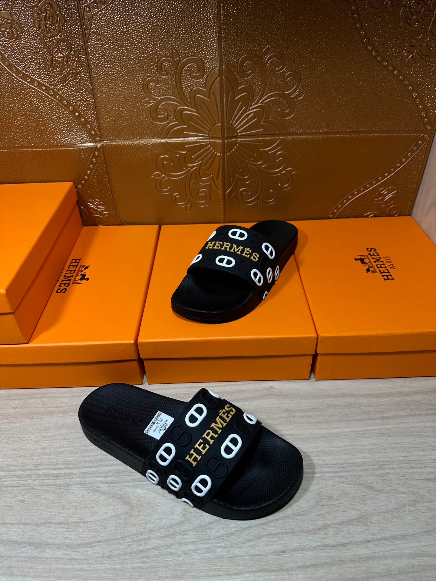 Black slide sandals with Hermes logo strap, one pair on display