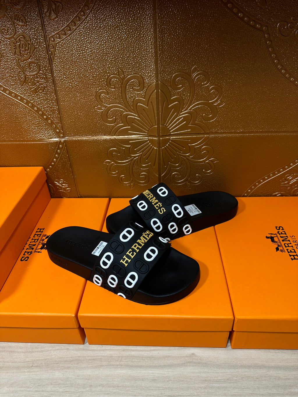 Black slide sandals with Hermes logo strap, close pair view