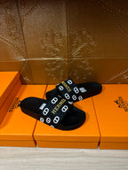 Black slide sandals with Hermes logo strap, close pair view