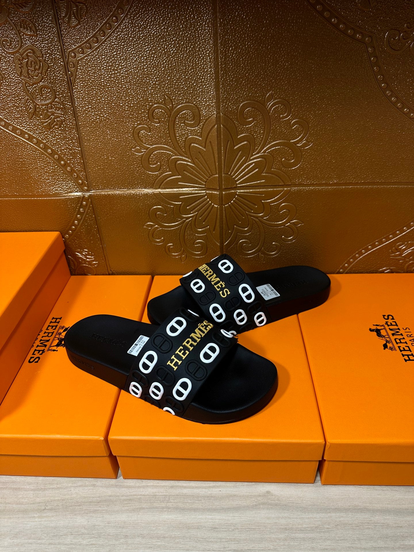 Black slide sandals with Hermes logo strap, close pair view