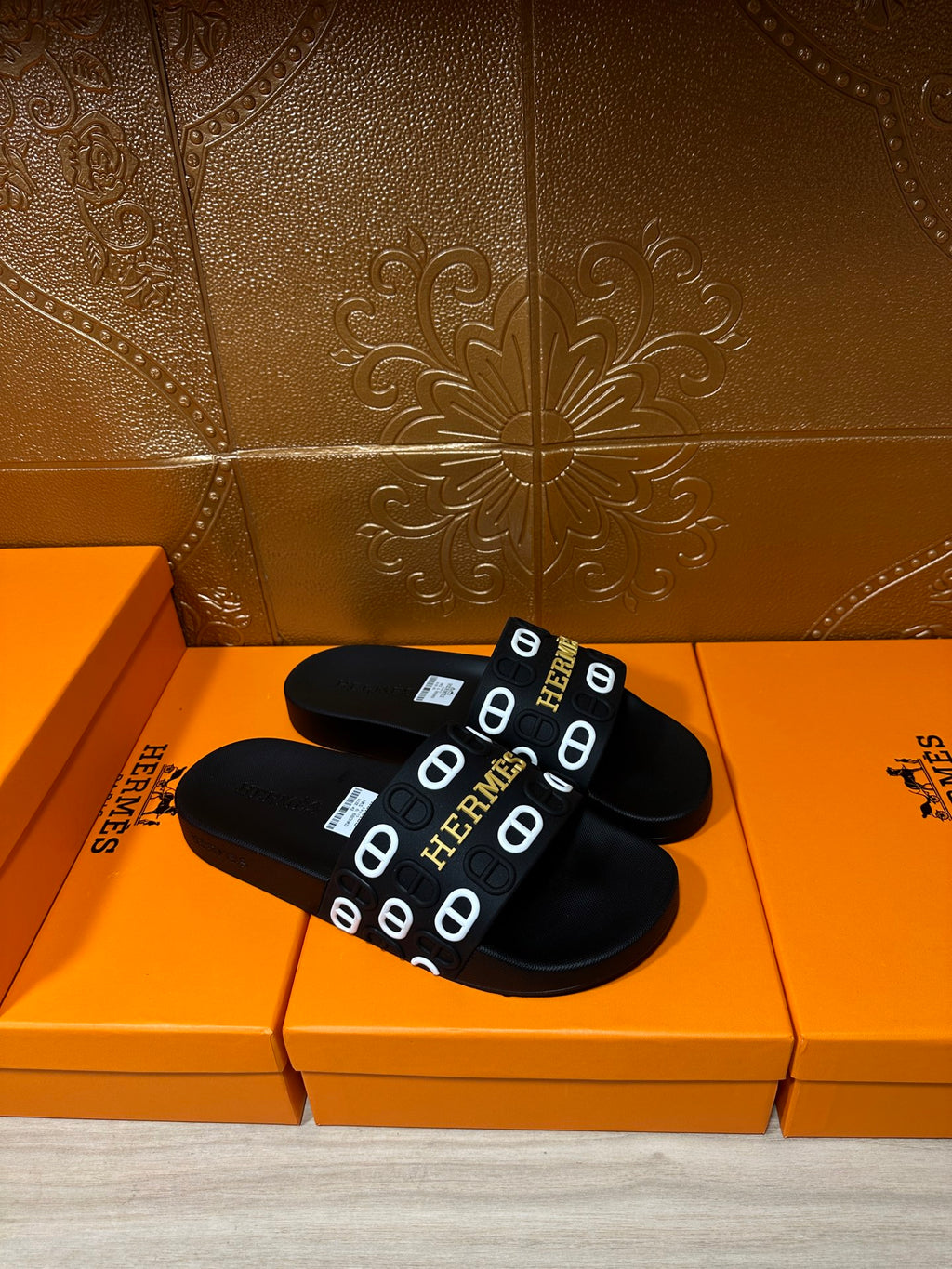 Black slide sandals with Hermes logo strap, angled pair view