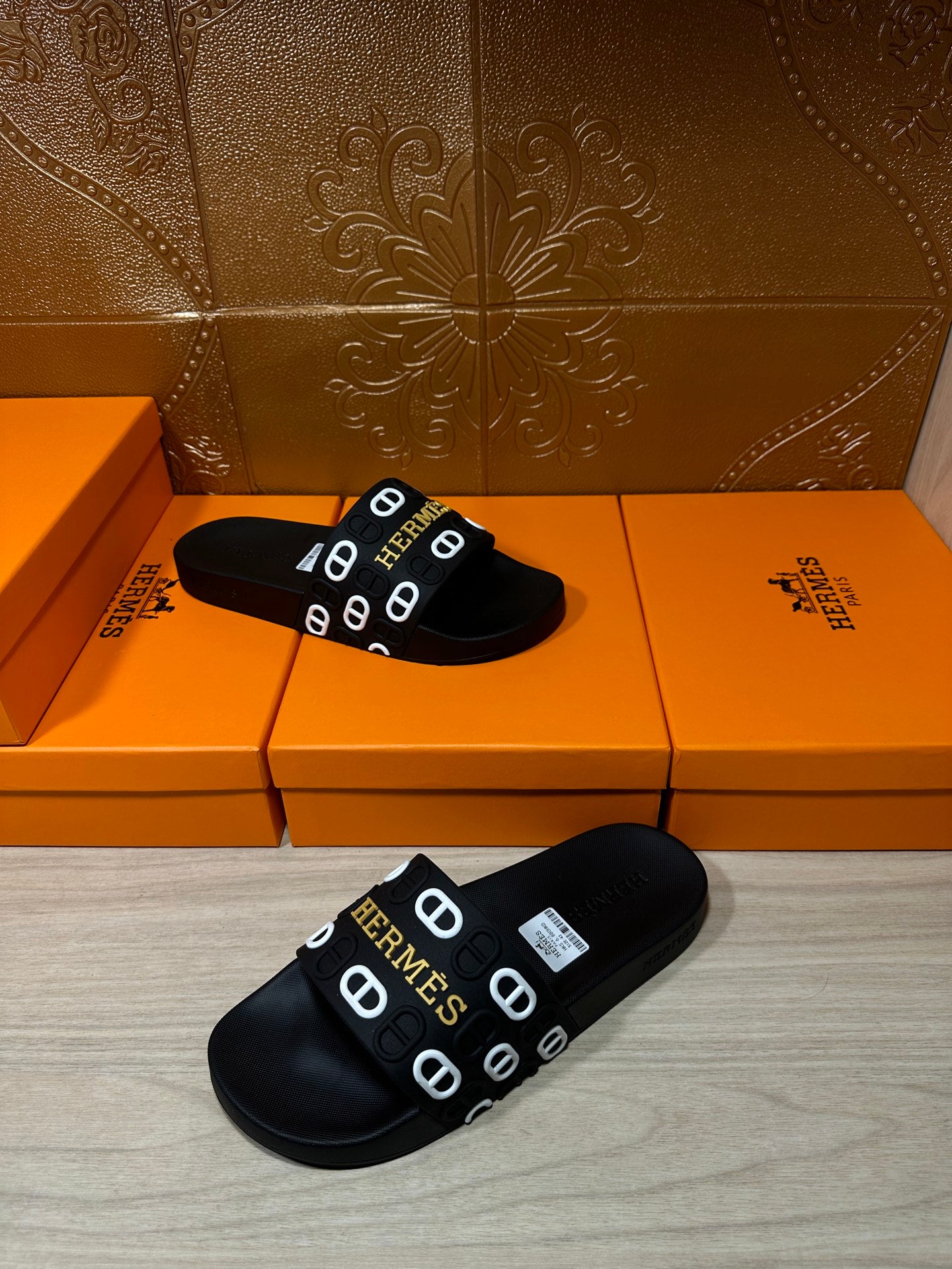 Black slide sandals with Hermes logo strap, angled view