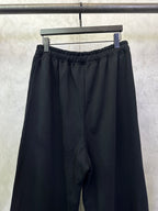 Black wide-leg pants with elastic waistband and draped fabric