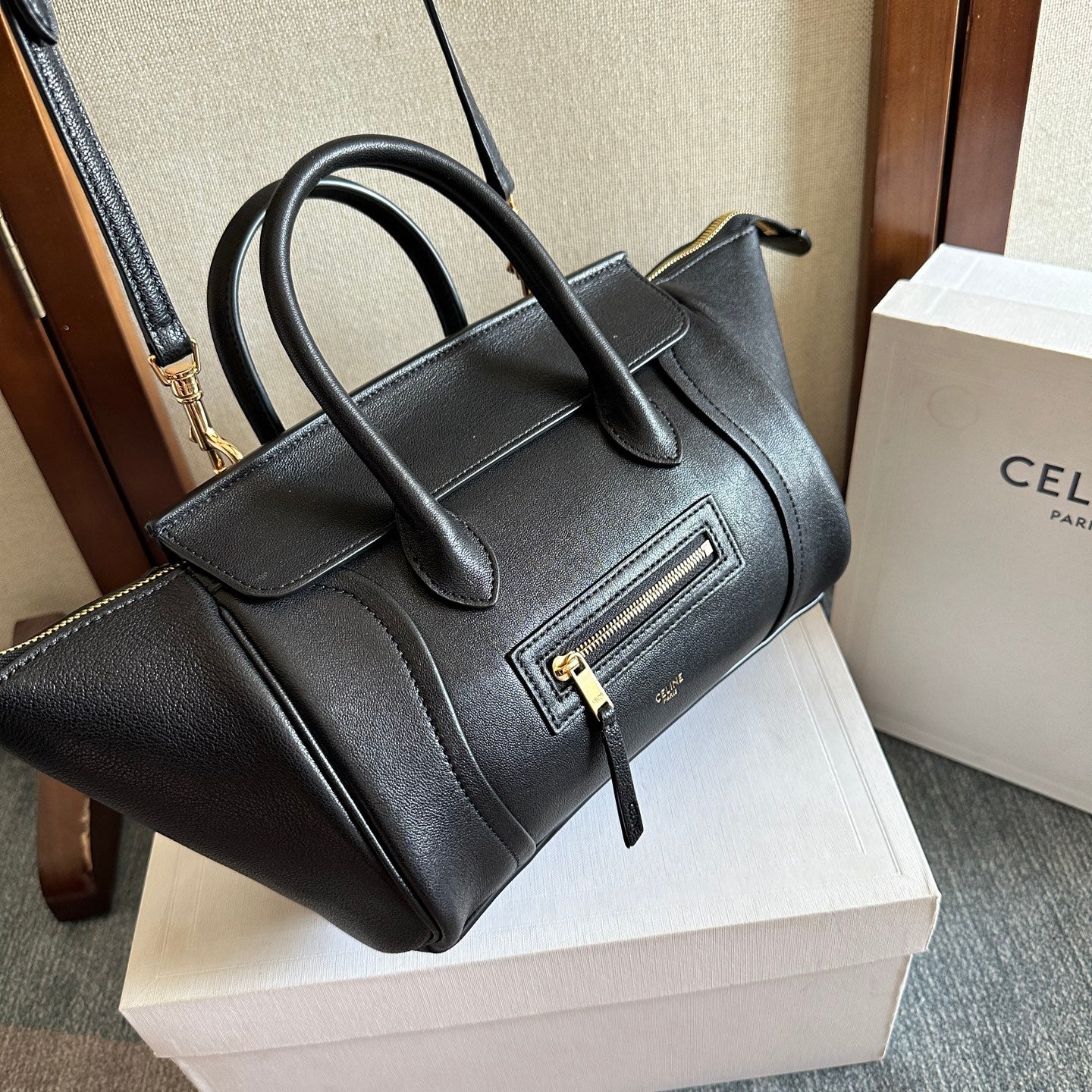 Celine handbag in dark leather with top handles, front zipper pocket, and gold hardware