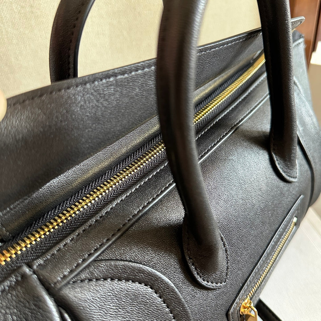 Celine handbag side view with gold-tone zippers, stitched seams, and dark leather handle