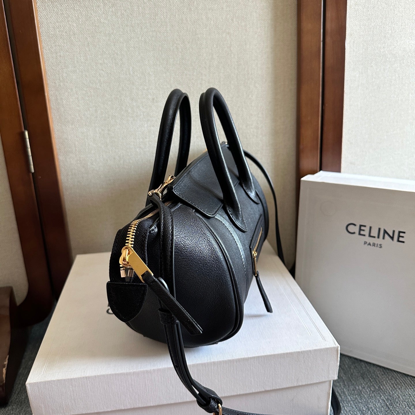 Celine handbag in dark leather with gold-tone hardware, top handles, and adjustable crossbody strap