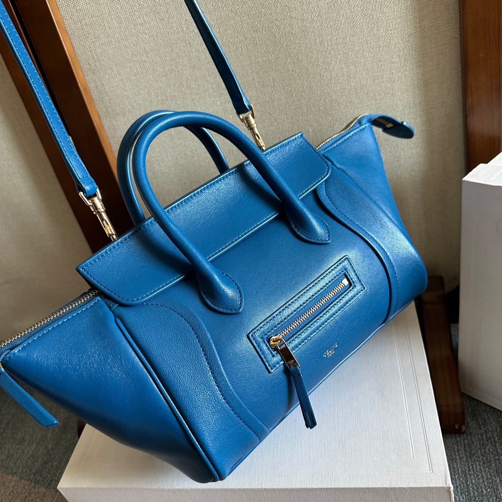 Blue leather top-handle bag with long crossbody strap and front zipper pocket