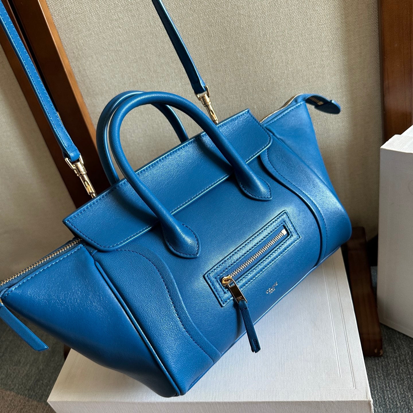 Blue leather top-handle bag with long crossbody strap and front zipper pocket