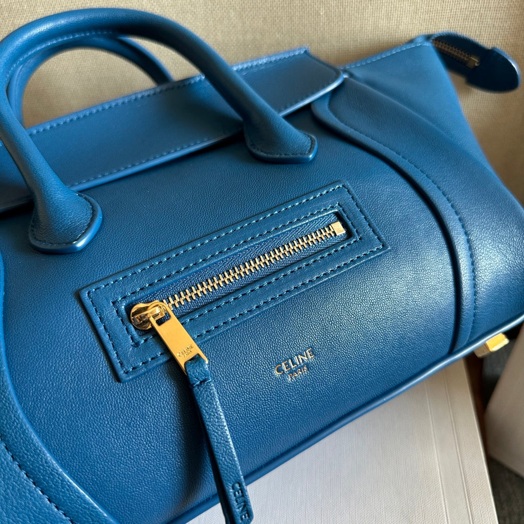 Blue leather bag front panel with embossed logo and gold zipper pull