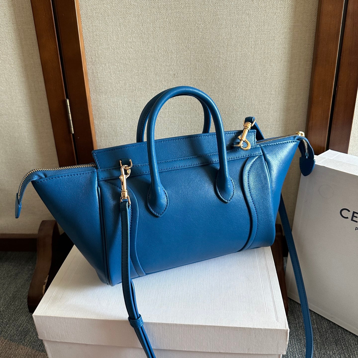 Blue leather top-handle bag with detachable strap and gold corner accents