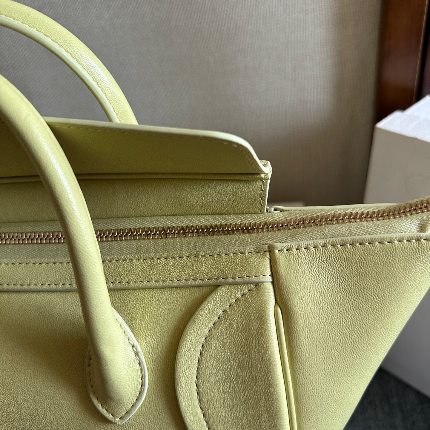 Light yellow Celine bag close-up of top seam, strap loop, and zipper