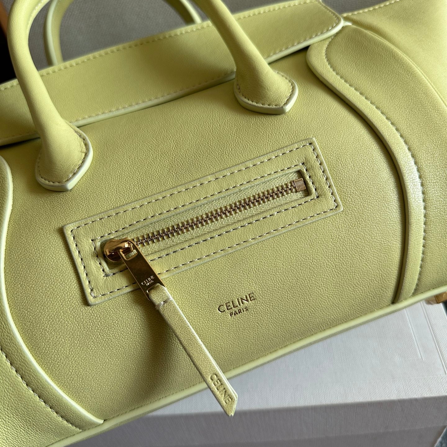 Light yellow Celine bag close-up of front zipper pocket and stitched logo