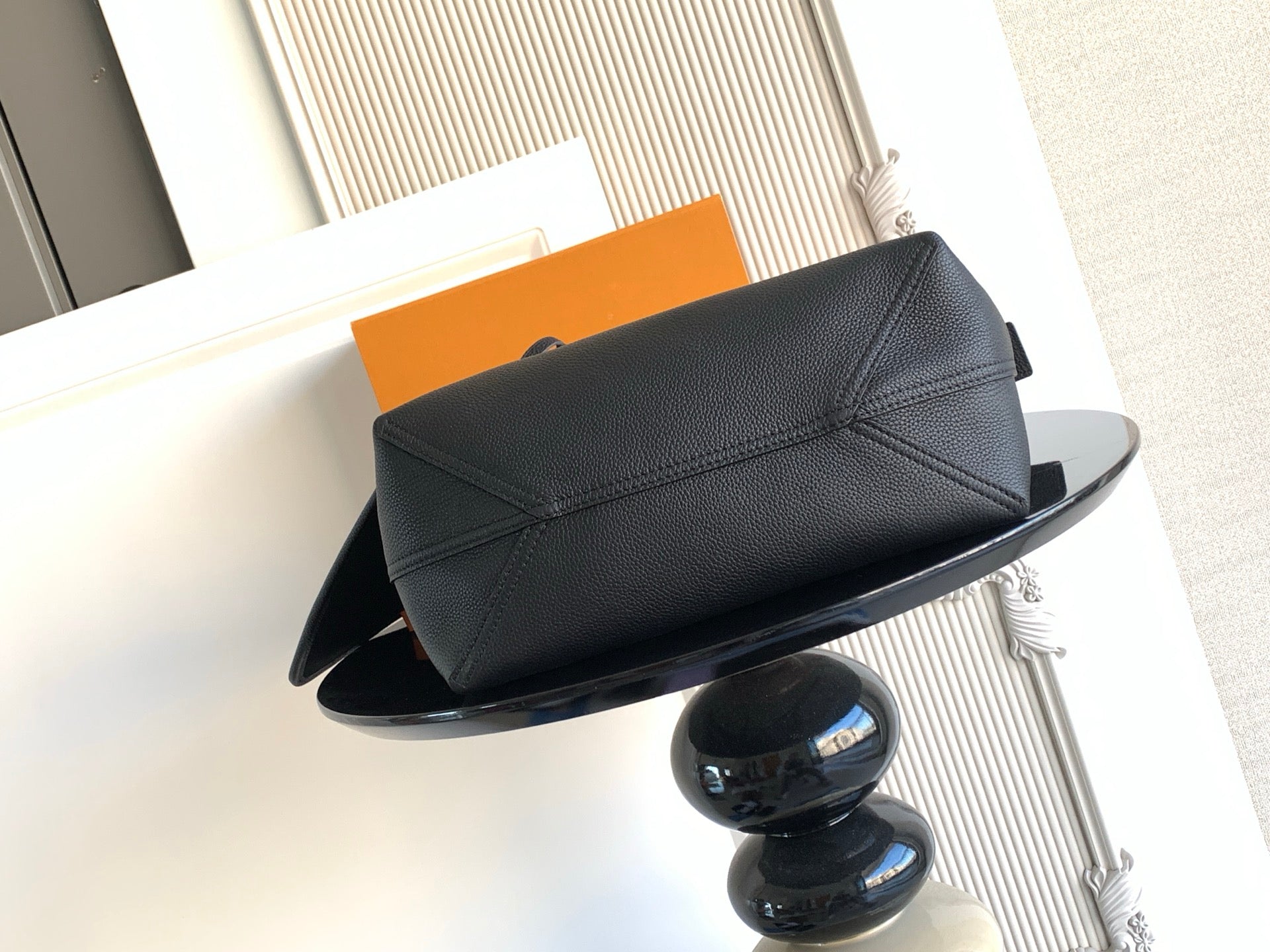 Black leather bag with top flap and stitched panel