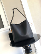 Black leather shoulder bag with curved top and long crossbody strap
