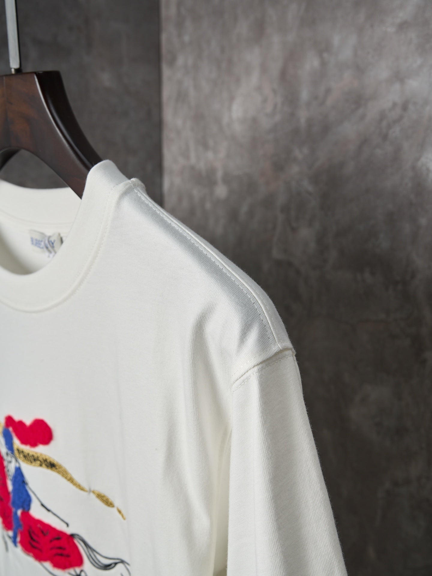 White short-sleeve T-shirt on hanger, side seam and shoulder visible