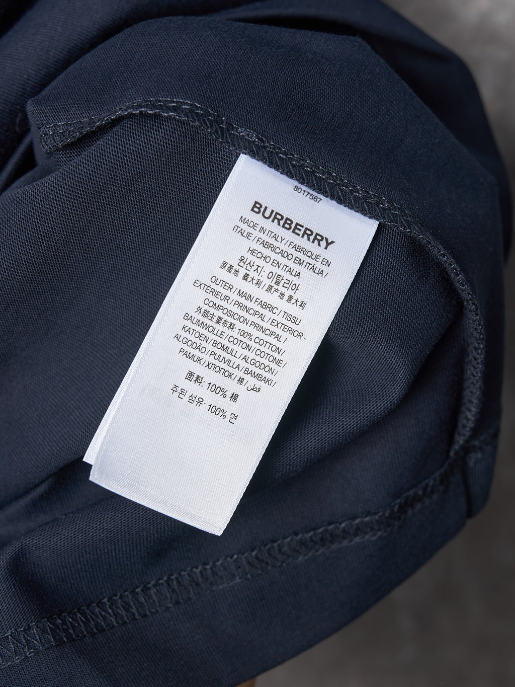 Navy T-shirt sleeve detail with white “BURBERRY” care label tag