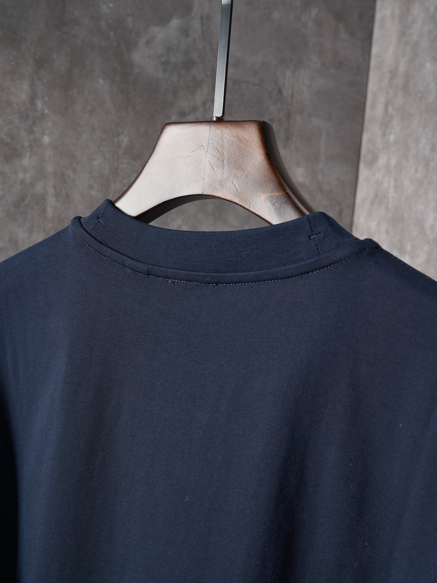 Navy crew-neck T-shirt back view on a hanger