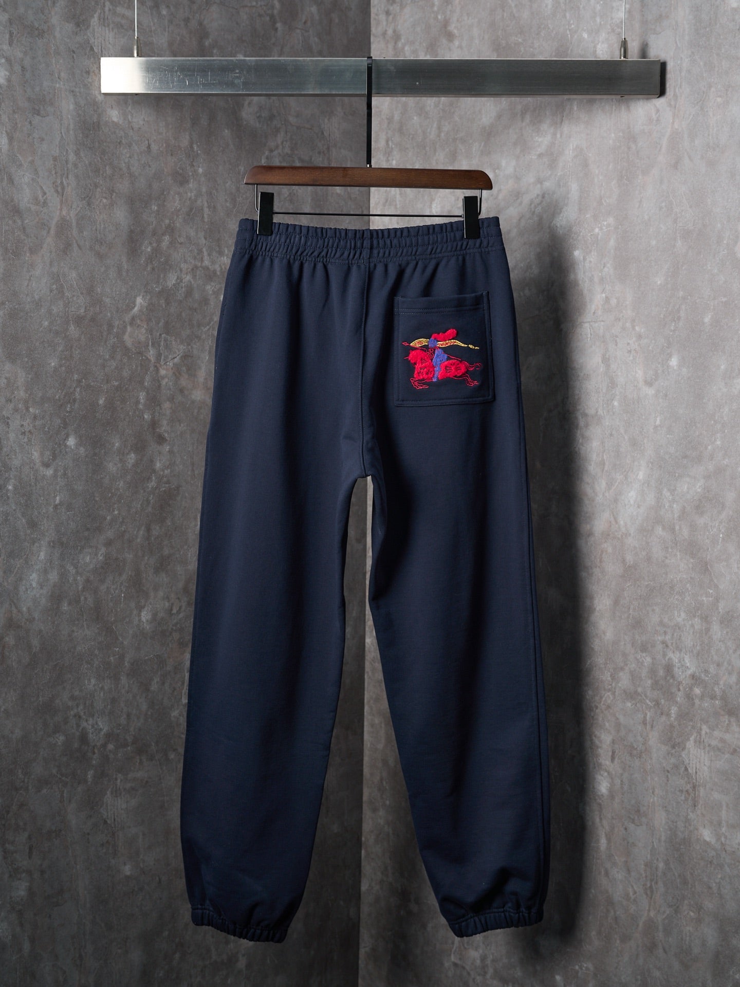 Navy jogger pants with a red horse logo on the front pocket
