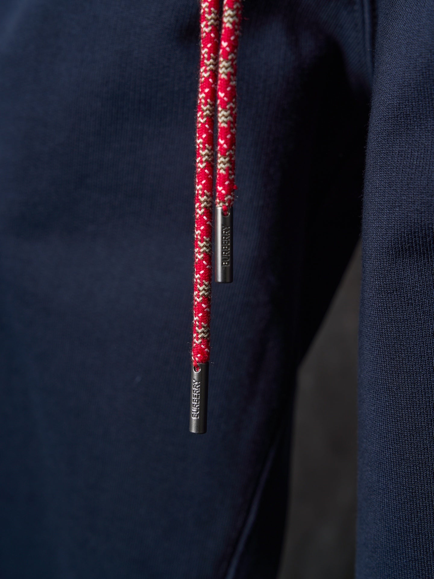 Navy drawstring with red patterned cord and metal tips