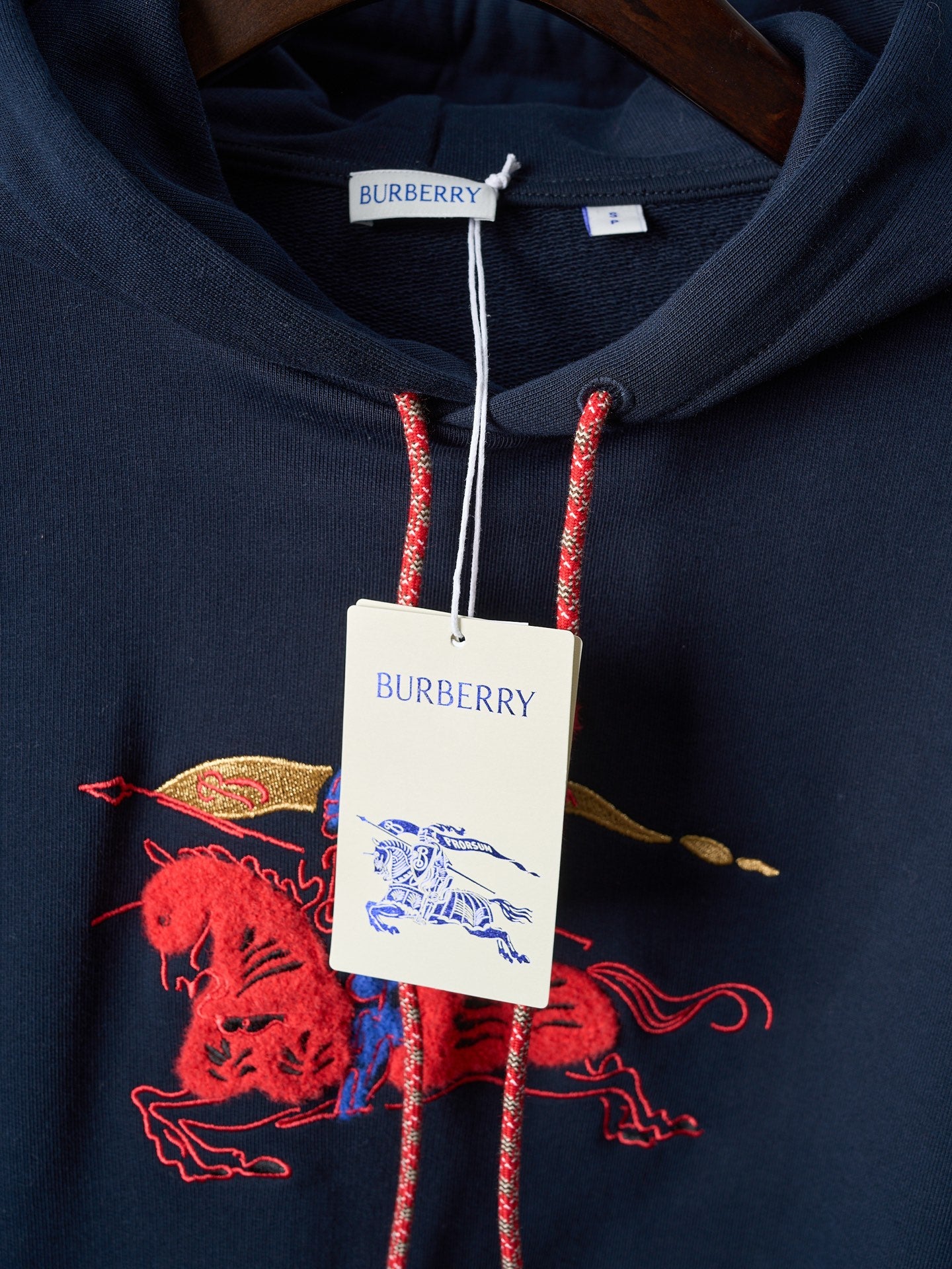 Navy hoodie with Burberry neck label and red drawstrings over chest graphic